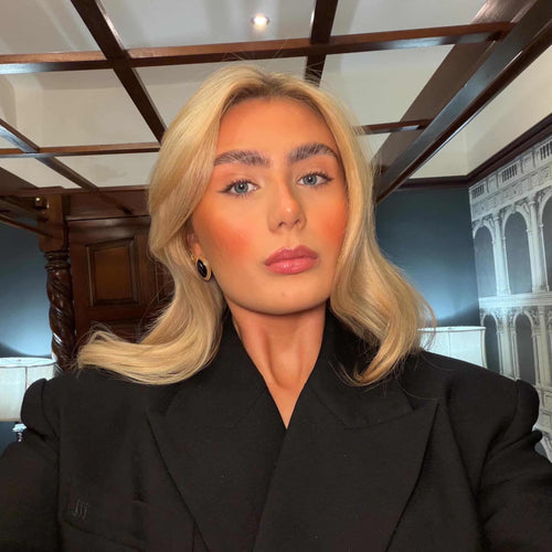 Person wearing a black coat in an indoor setting with decorative ceiling and wall.